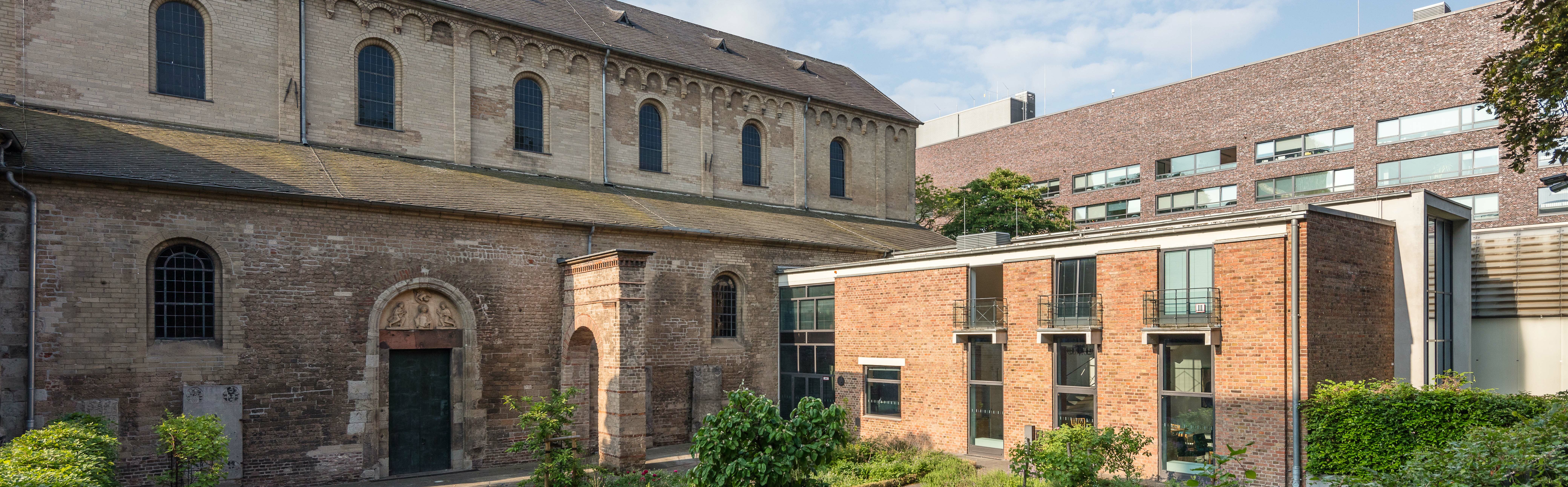 [Translate to English:] Blick auf den Garten des Museum Schnütgen im Frühjahr, sowie auf die Cäcilienkirche und den Annexbau aus den 1950er Jahren.