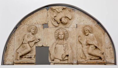 Im Zentrum des Halbskreisförmigen Steinreliefs steht eine Frau mit Heiligenschein. An ihrer Seite befindet sich jeweils ein Mann, über ihr beugt sich ein Engel zu ihr hinab.