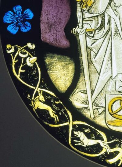 Ranken mit Eicheln und Hunden auf dem Rand einer Scheibe.