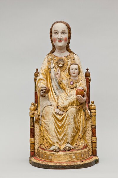 Farbig bemalte Holzfigur einer sitzenden Frau. Auf ihrem Schoß sitzt ein Kind. Die Gewänder der beiden sind gold-gelb.