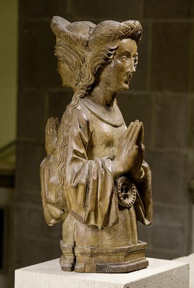 Büste einer Frau mit zum Gebet gefalteten Händen. Sie steht Rücken an Rücken mit ihrem eigenen Abbild.