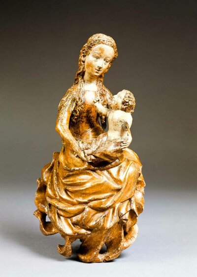 Figur einer sitzenden Maria mit Jesuskind auf ihrem Schoß. Beide sind sich zugeneigt.