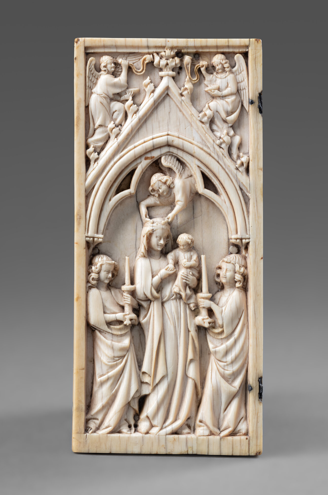 Elfenbeinschnitzerei: Ein Engel setzt Maria eine Krone auf. Sie hält dabei das Jesuskind auf dem Arm, rechts und links stehen weitere Engel mit Kerzen, oben weitere Engel 