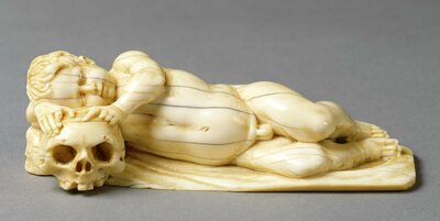 Im Liegen schlafender Putto. Wie auf einem Kissen liegt sein Kopf auf einem Totenschädel.