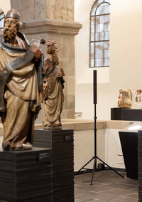 Lautsprecher in der Ausstellung. Im Vordergrund stehen zwei mittelalterliche Plastiken