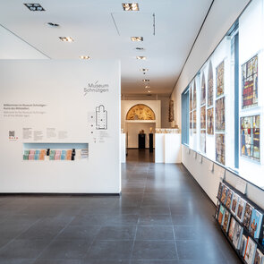 [Translate to English:] Blick in den lichtdurchfluteten Eingangsbereich im Neubau des Museum von 2010 mit Willkommenstafel und Glasmalereien