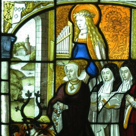 Die Glasmalerei zeigt mehrere betende Frauen. Über ihnen steht eine Frau mit Heiligenschein. In ihrer Hand hält sie eine Orgel.