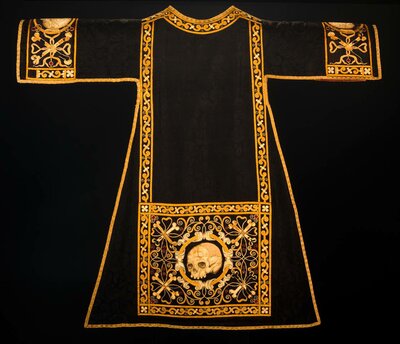 Liturgisches schwarzes Gewand mit goldener Verzierung und stilisierten Totenschädeln an Ärmeln und am Saum 
