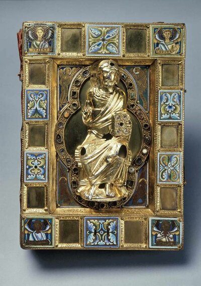 Vorderseite eines Buches. Im Zentrum steht die goldene Figur eines sitzenden Mannes. Dieser hält in seiner linken Hand ein Buch. Seine rechte ist erhoben.