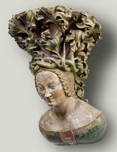 Steinbüste einer jungen Frau im Profil. Auf ihrem Kopf trägt sie eine sich rankende Blätterkrone.