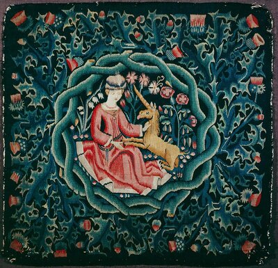 Quadratisches Stoffstück. Im Zentrum der Bestickung steht die Abbildung einer sitzenden Frau. Ein Einhorn hat die Vorderhufe in ihren Schoß gelegt.