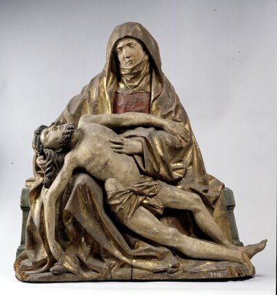 Holzfigur der sitzenden Maria mit dem verstorbenen Jesus in ihrem Schoß. Maria trägt ein ausladendes, goldenes Gewand.
