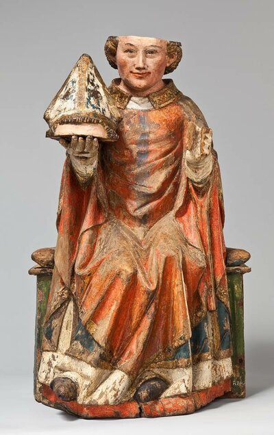 Holzfigur des Hl. Dionysius. In seiner rechten Hand hält er seinen abgetrennten Skalp, auf dem ein Bischhofshut sitzt.