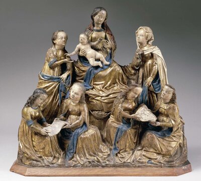 Holzschnitzerei: Maria mit Kind inmitten weiterer sechs Frauen. Die vorderen Frauen halten Schriftstücke in ihren Händen.