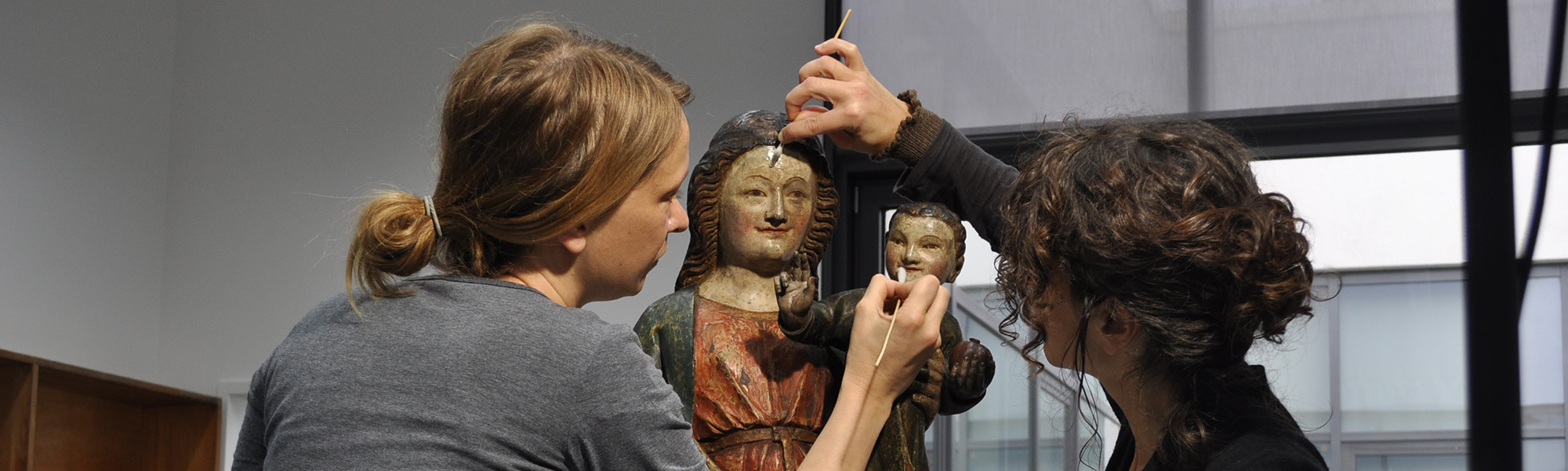 Zwei Restaurateurinnen arbeiten an einer Statue